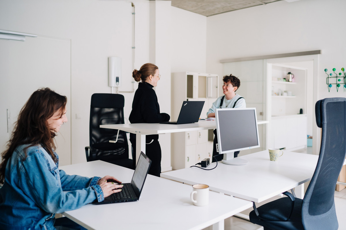 Junge Menschen arbeiten im CoWorking Bereich am höhenverstellbaren Tisch