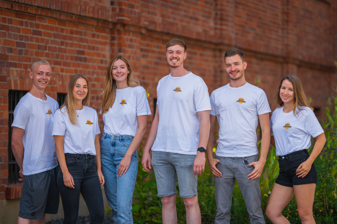 Das Team von stay awesome vor einem roten Backsteingebäude. Es handelt isch um sechs Personen von denen drei weiblich und drei männlich sind.