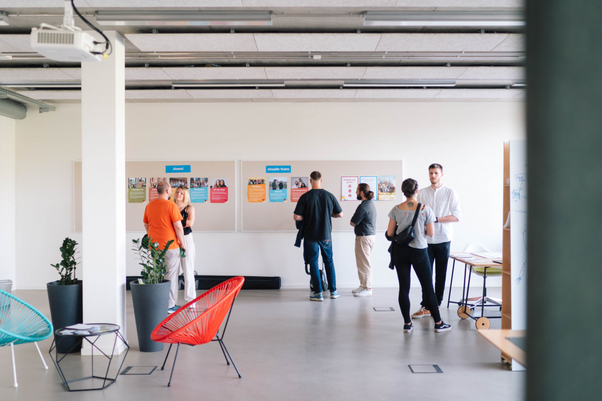 mehrere Menschen stehen im CoCreationLab, einem große Raum zum gemeinsamen Arbeiten, und tauschen sich aus.