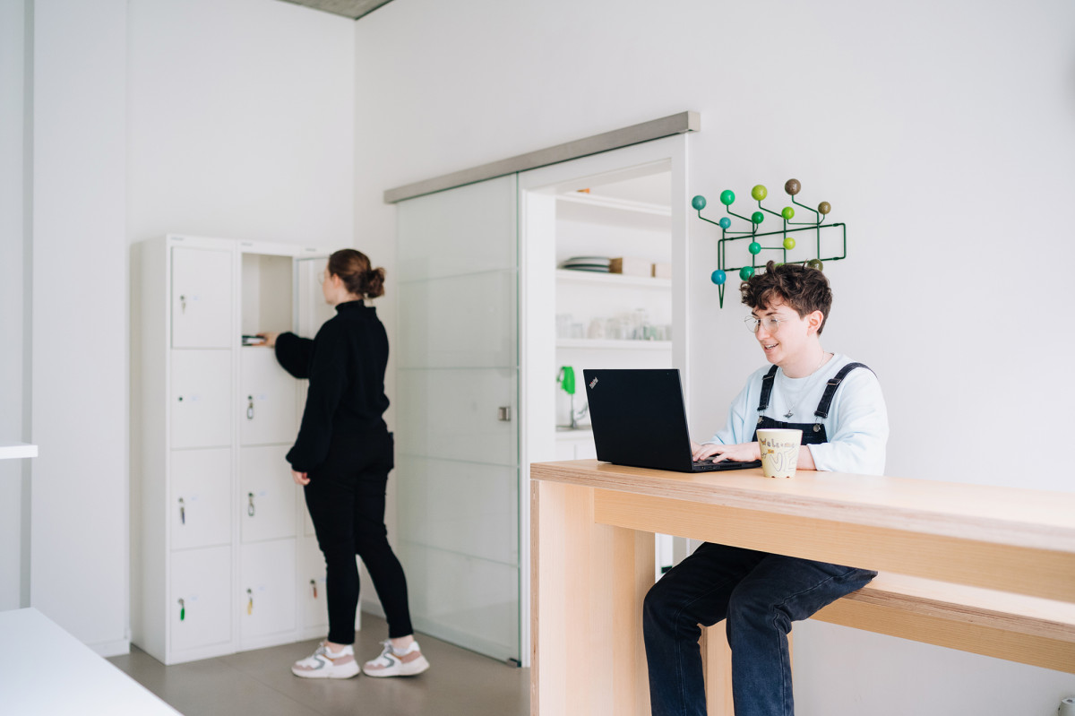 Junge Menschen arbeiten im CoWorking Bereich und legen ihre Wertsachen in die Schließfächer